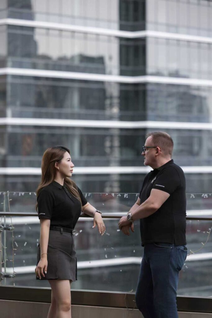 Zwei Menschen in schwarzer Kleidung unterhalten sich ernsthaft auf einer Dachterrasse