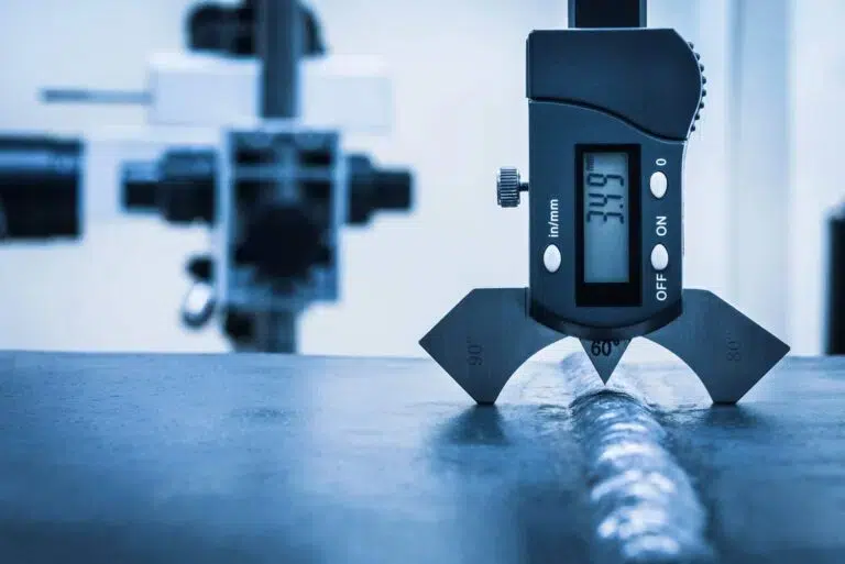 Ein digitales Messgerät misst präzise eine metallene Schweißnaht in Blauweiß