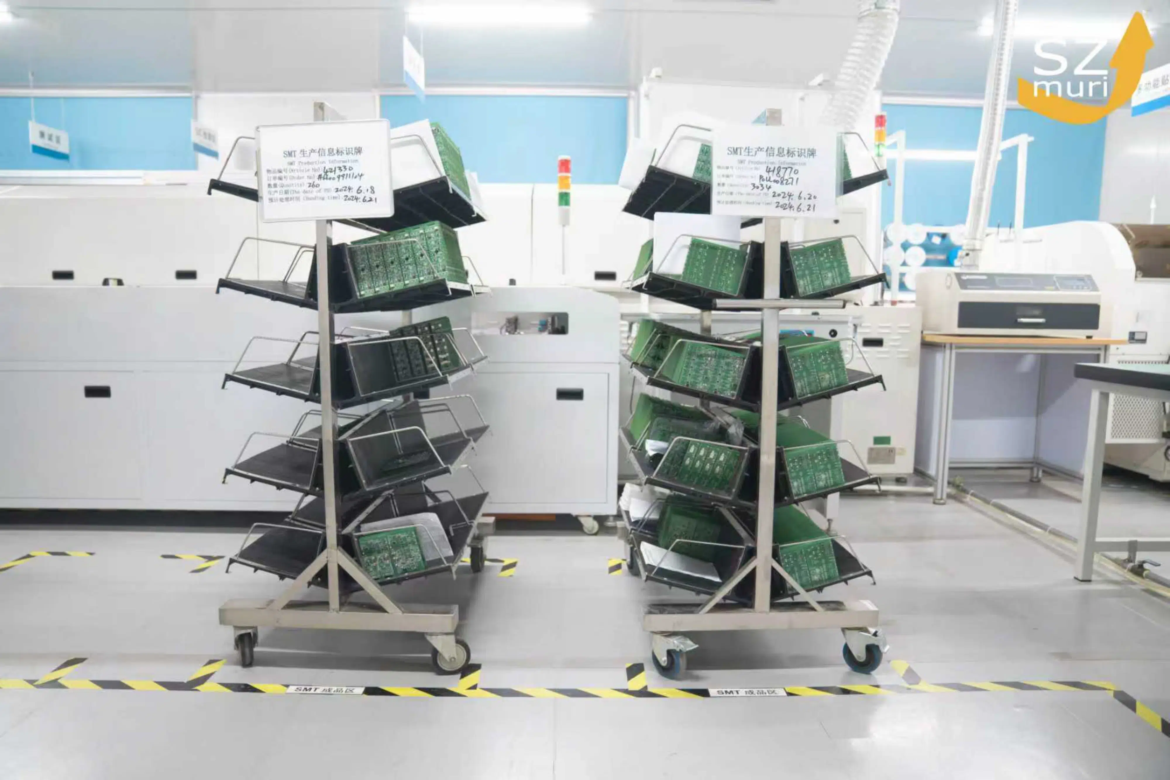 Zwei Wagen mit grünen Leiterplatten stehen in einem hellen Elektroniklabor