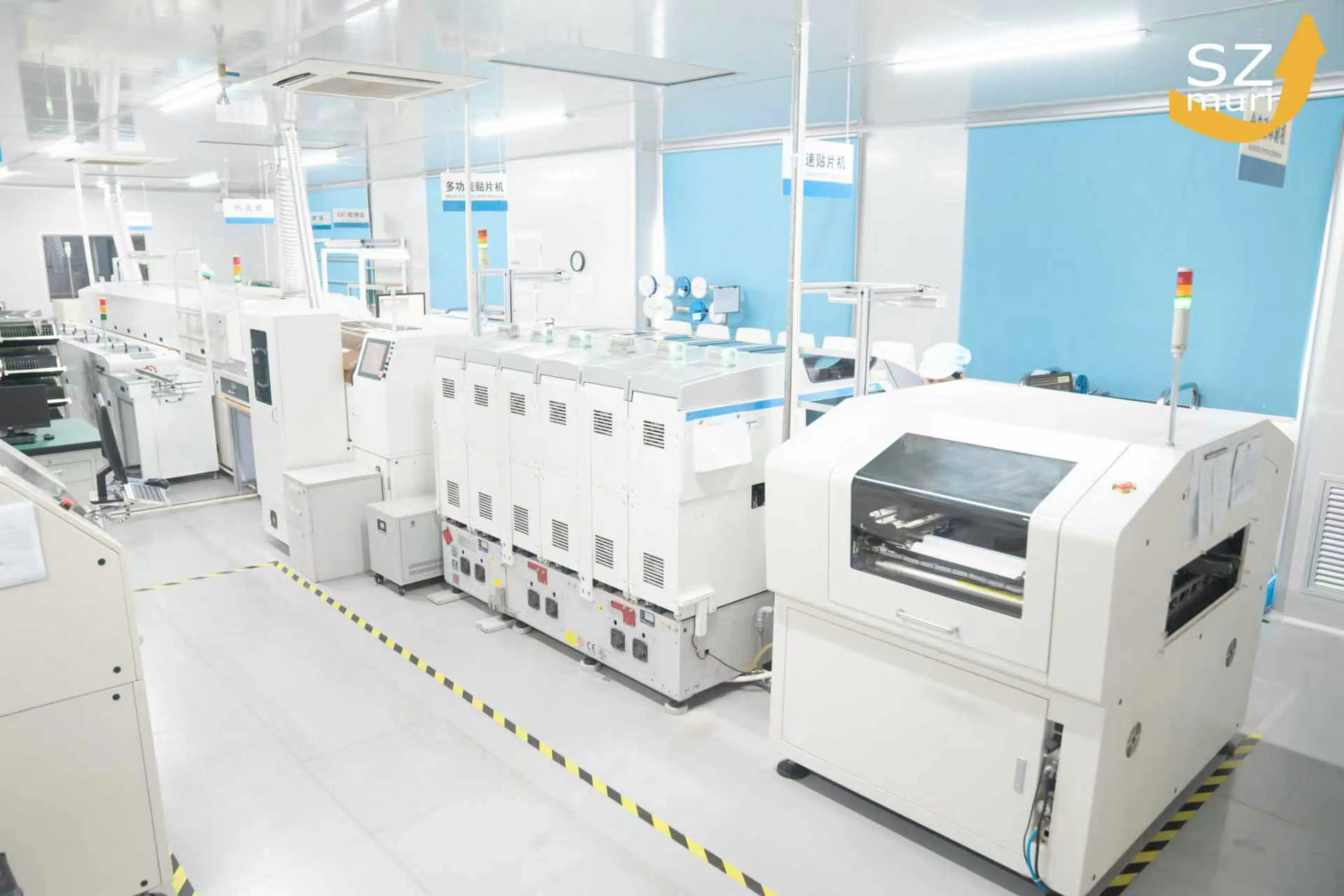 Ein moderner, heller Fabrikraum mit mehreren weißen Fertigungsmaschinen und gelbem Licht