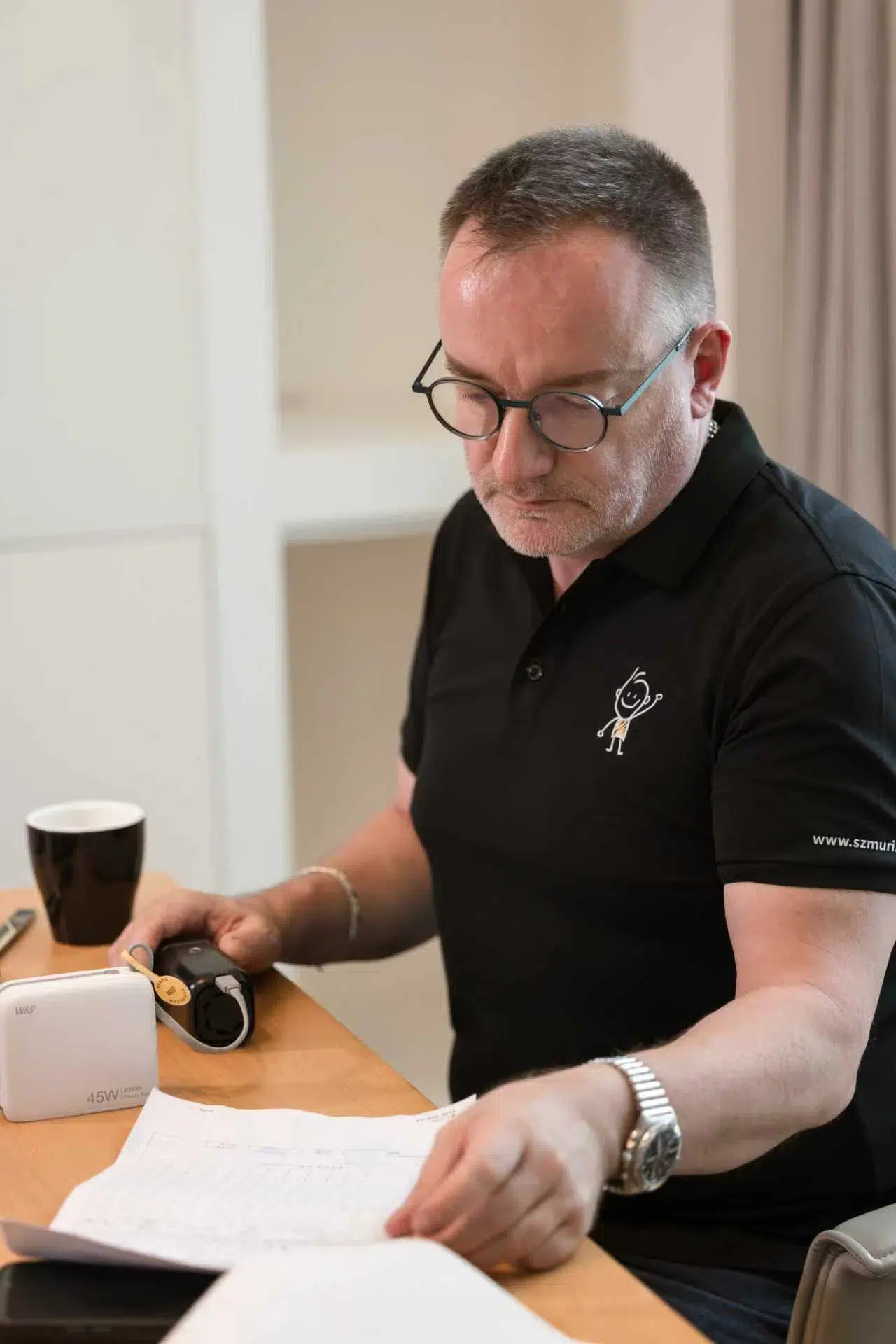 Ein Mann mit Brille und kurzem Haar blickt konzentriert auf Unterlagen am Tisch